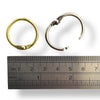 Two hinged rings next to a ruler for size reference on a white background