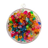 A collection of small transparent multi coloured Plastic Rondell Beads in a round container on a white background.