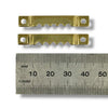 Two small brass-colored sawtooth hangers with circular holes and a serrated center edge, shown above a metal ruler for scale on a white background.