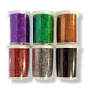 Six clear plastic jars filled with glitter in assorted colors, arranged in two rows of three on a white background. The glitter colors include purple, green, copper, red, multi coloured, and black.