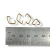 Four triangle jump rings in a gold colour with a ruler for scale on a white background